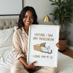 Woman in a bedroom holding a framed picture with a humorous quote about procrastination and a cat in a box.