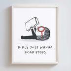Framed artwork with a black and white illustration of a girl holding a book and text 'Girls just wanna read books' on a white background.