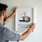 Man hanging a framed illustration on a wall with text 'Girls Just Wanna Read Books'.