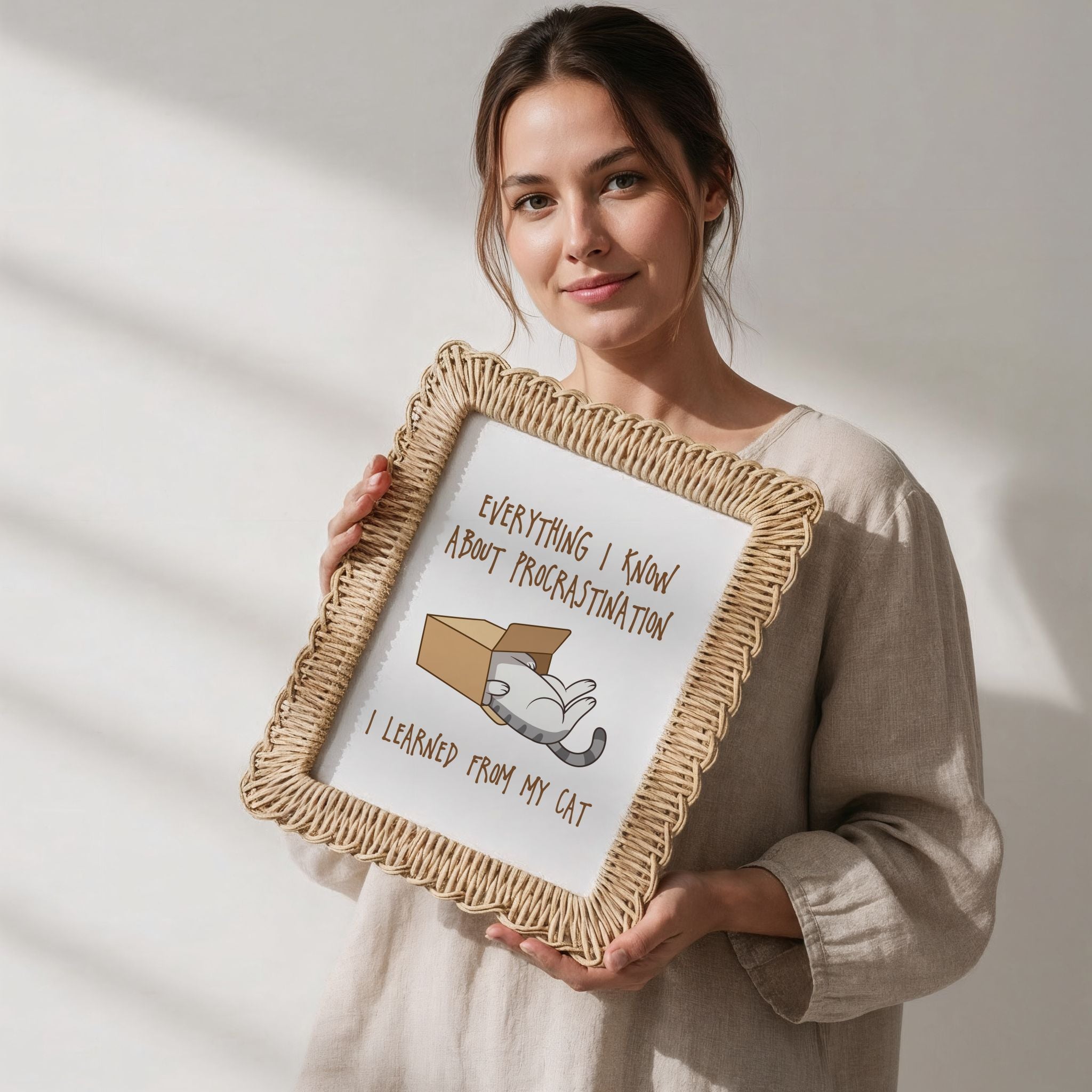 Woman holding a rattan-framed picture with humorous text about procrastination and a cat.
