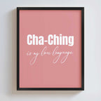 Framed pink poster with 'Cha-Ching is my love language' text on a white wall.
