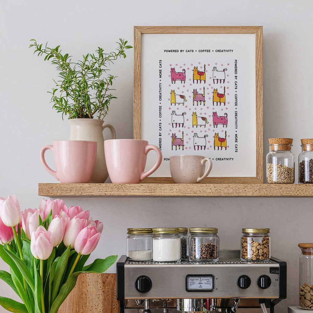 Kitchen shelf with pink mugs, a plant, a framed print, and jars on a light gray wall over a coffee machine.