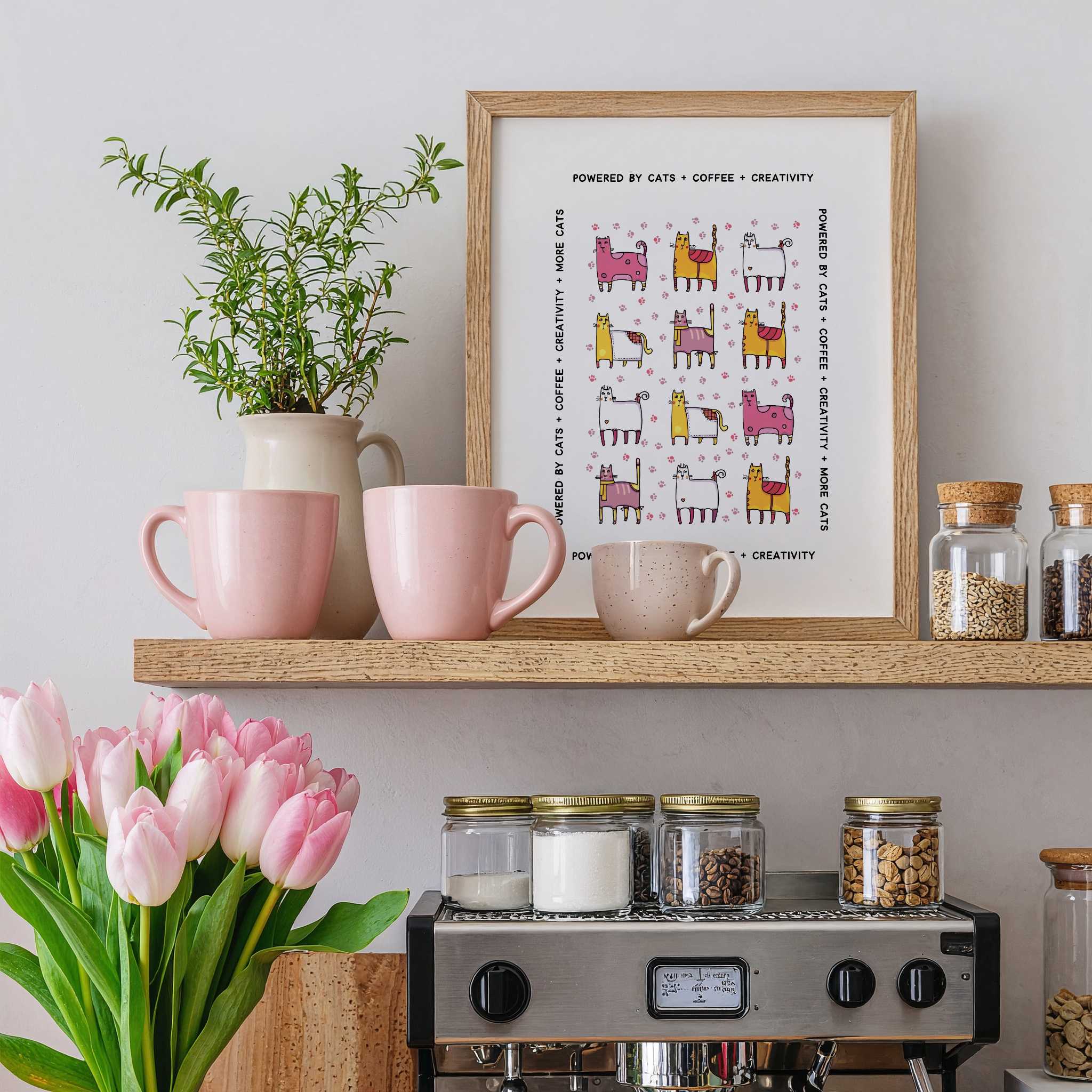 Kitchen shelf with pink mugs, a plant, a framed print, and jars on a light gray wall over a coffee machine.