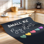 Unframed print with 'Small Biz Big Heart' text and colorful hearts on a wooden counter.